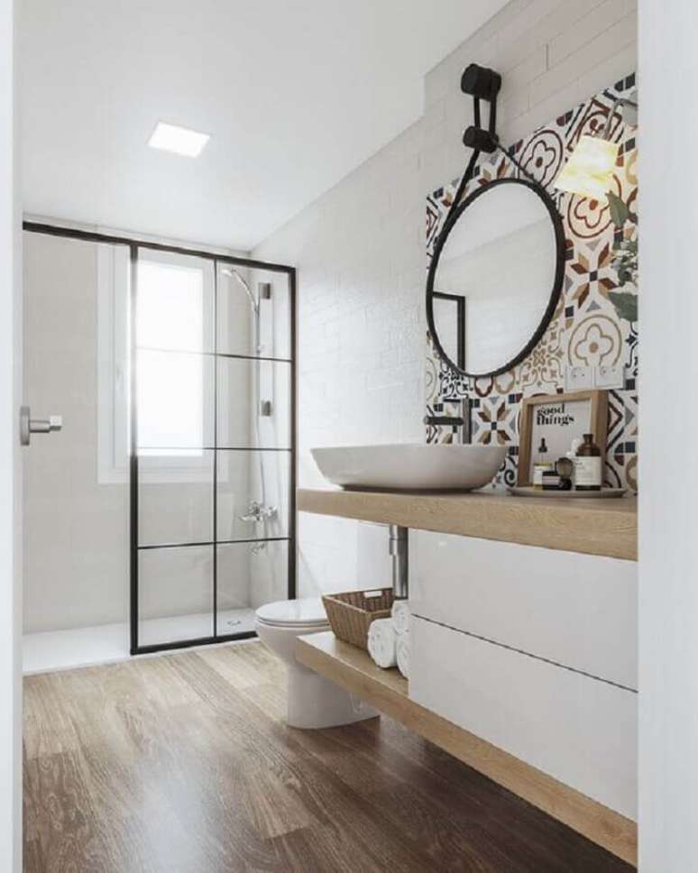 48. Espelho redondo e ladrilho hidráulico para decoração de banheiro com piso de madeira – Foto: Iglû Estúdio
