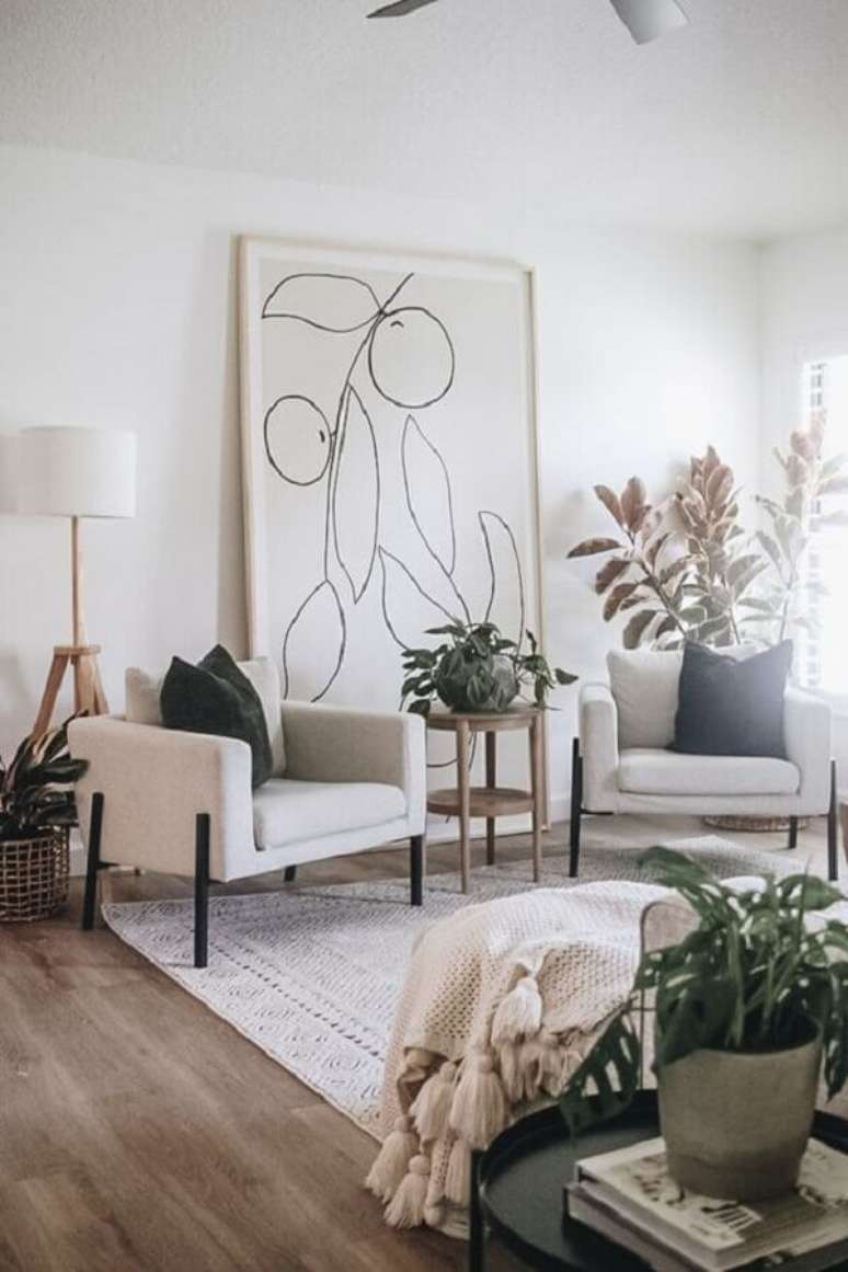 51. Poltrona branca para sala decorada com vasos de plantas e quadro grande – Foto: Casa Tres Chic