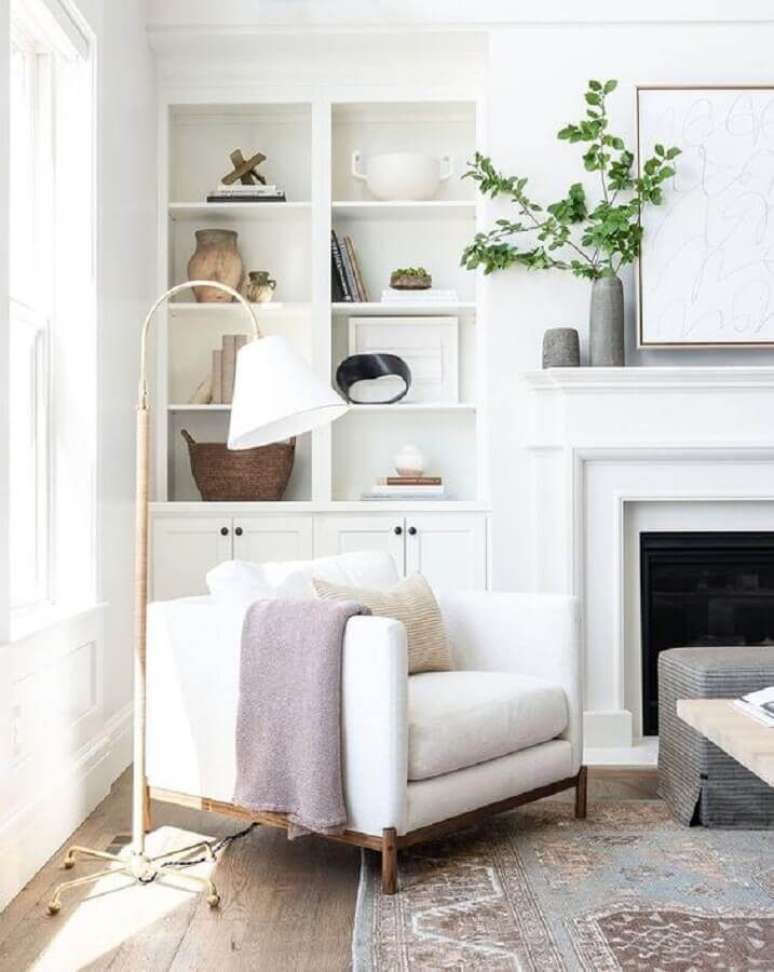 44. Poltrona branca para sala com lareira decorada com lumin&aacute;ria de piso e estante planejada &ndash; Foto: McGee e Co.