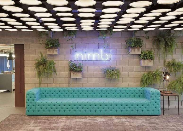 1. Decoração com vasos de plantas na parede e sofá cor ciano capitonê – Foto: Melina Romano Interiores