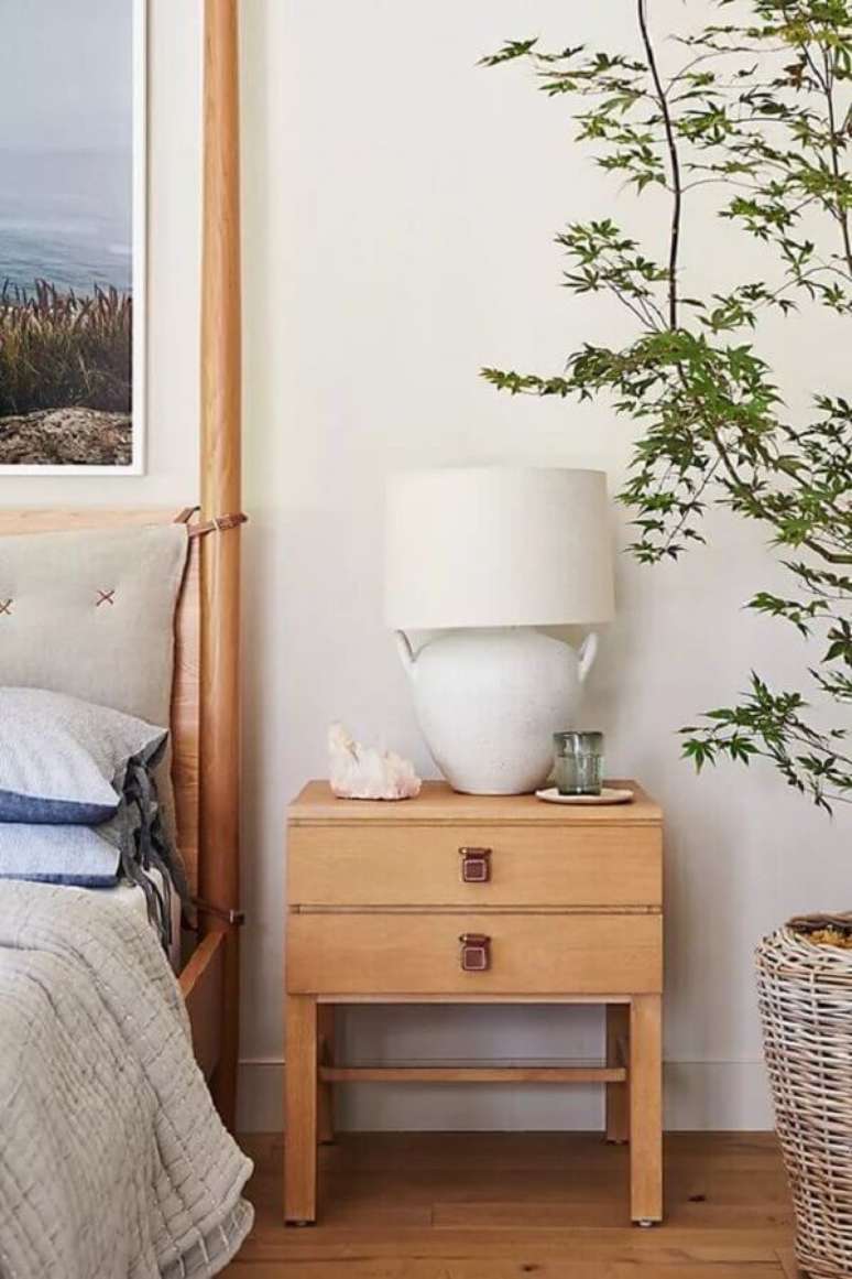 12. Abajur para criado mudo de quarto decorado com vaso de plantas e moveis de madeira – Foto: Anthropologie