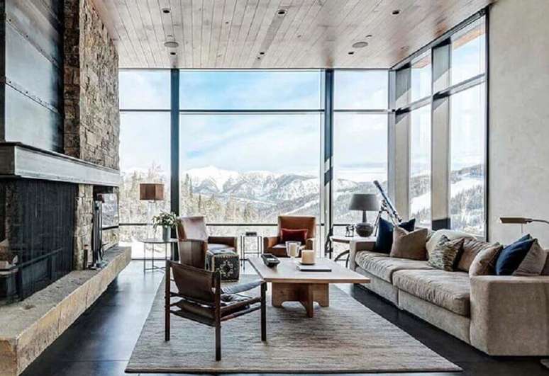 46. Revestimento de pedra para lareira de sala r&uacute;stica decorada com janela do ch&atilde;o ao teto &ndash; Foto: Houzz