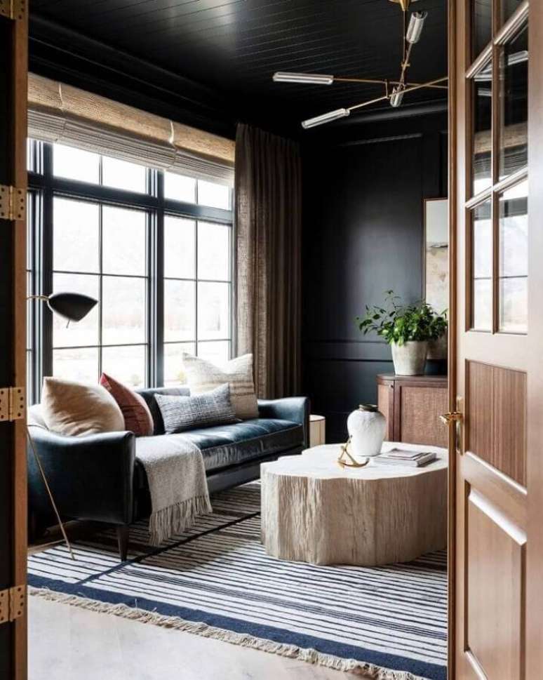 57. Sofá preto de couro para decoração de sala rústica com tapete listrado – Foto: Studio McGee