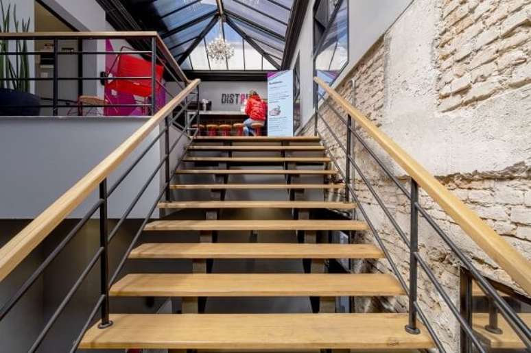 80. Estabelecimento com parede de tijolinho e escada de madeira. Fonte: Aurora Interiores