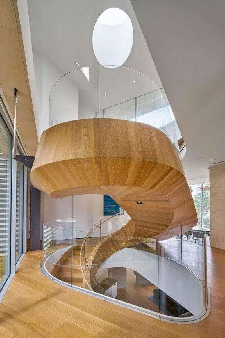 22. Escada caracol de madeira com guarda corpo de vidro levando modernidade e leveza para o ambiente. Fonte: One Kindesign