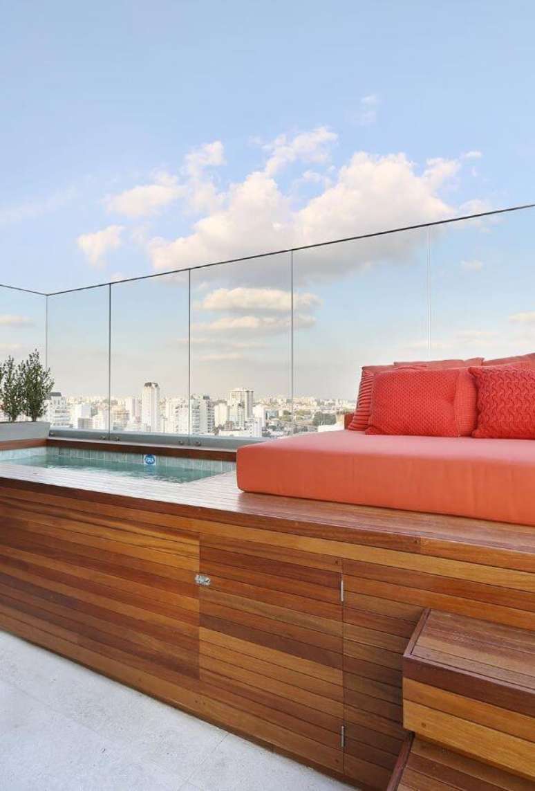 47. Quintal com piscina elevada e deck de madeira com sofá laranja -Foto Casa de Valentina