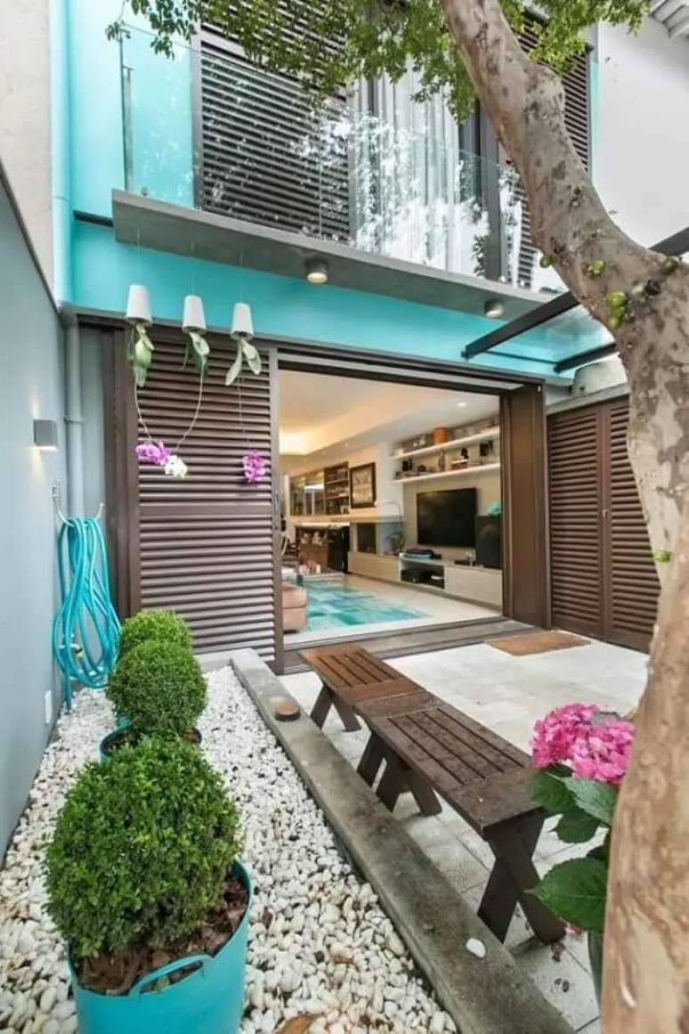 93. Jardim pequeno com pedras brancas, buchinho e orqu&iacute;deas suspensas trazem alegria para a casa simples. Fonte: DT Est&uacute;dio