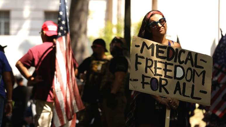 Mulher em protesto antivacina segurando cartaz em que se lê 'liberdade médica para todos'