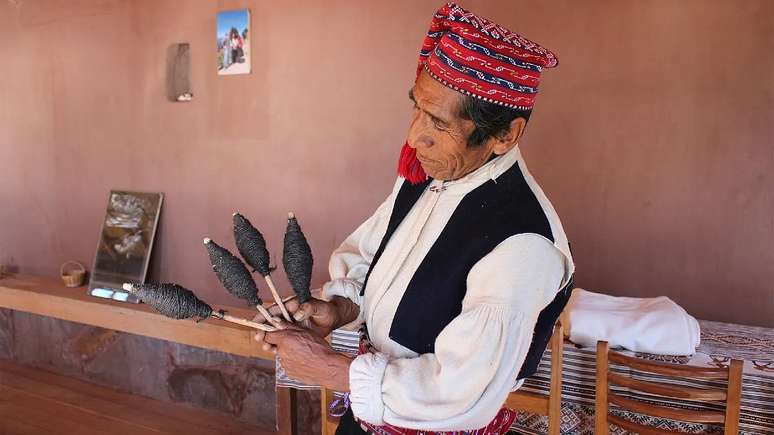 Alejandro Flores com seu chullo e a lã usada para produzi-lo; como os demais homens da ilha, ele aprendeu a técnica observando os mais velhos