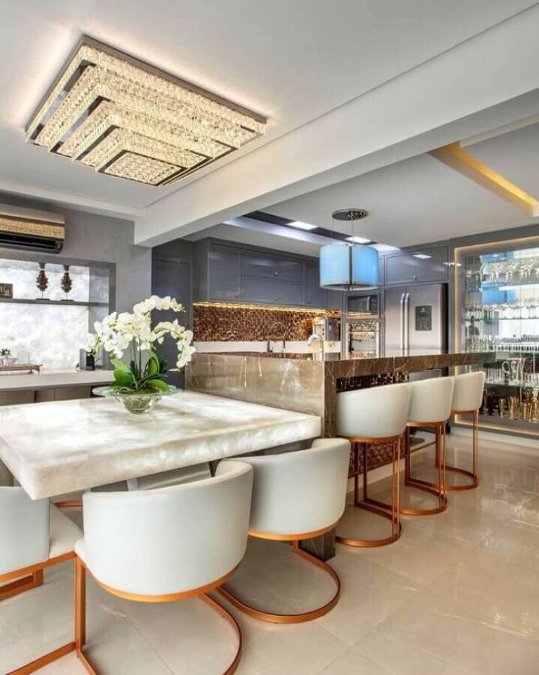 45. Decora&ccedil;&atilde;o moderna com cadeira estofada para cozinha de luxo com ilha de m&aacute;rmore &ndash; Foto: Iara Kilaris