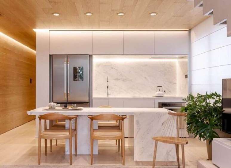 26. Cores claras para decoração de cozinha de luxo com ilha de mármore e cadeiras de madeira – Foto: Suite Arquitetos