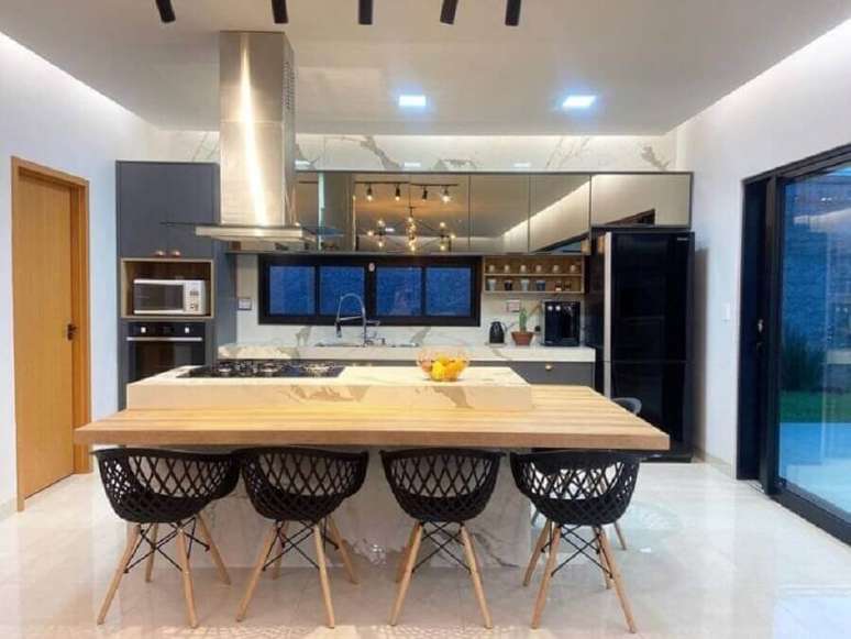 28. Decora&ccedil;&atilde;o de cozinha com ilha de m&aacute;rmore com cooktop e bancada de madeira &ndash; Foto: Thallyne Castro