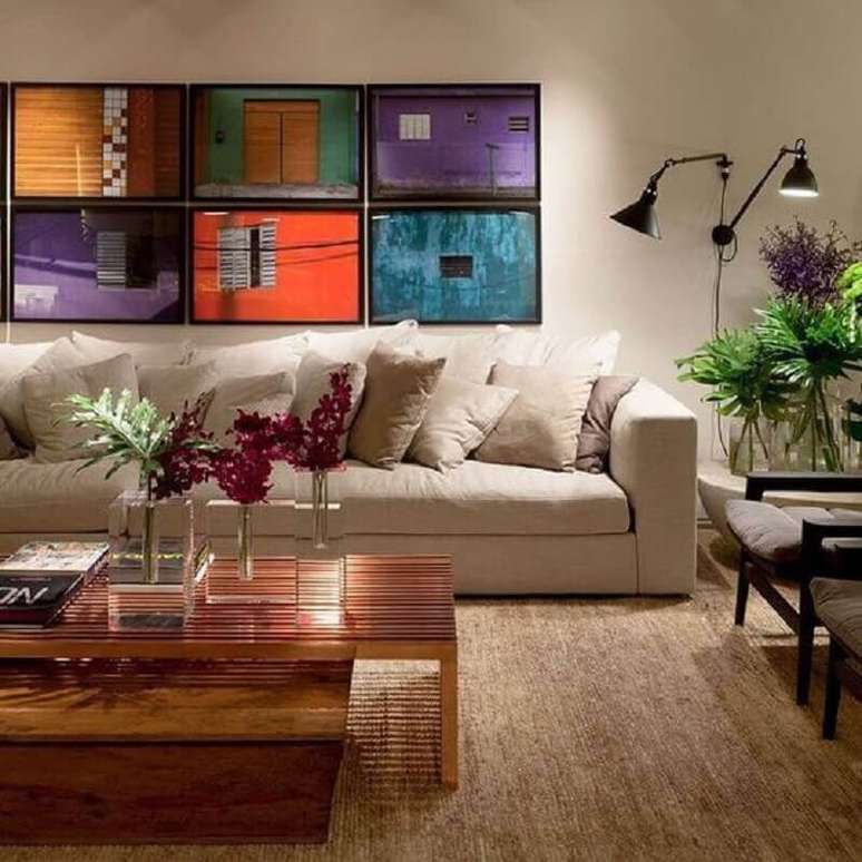 27. Iluminação para sala de estar decorada com quadros coloridos – Foto: Casa Casada
