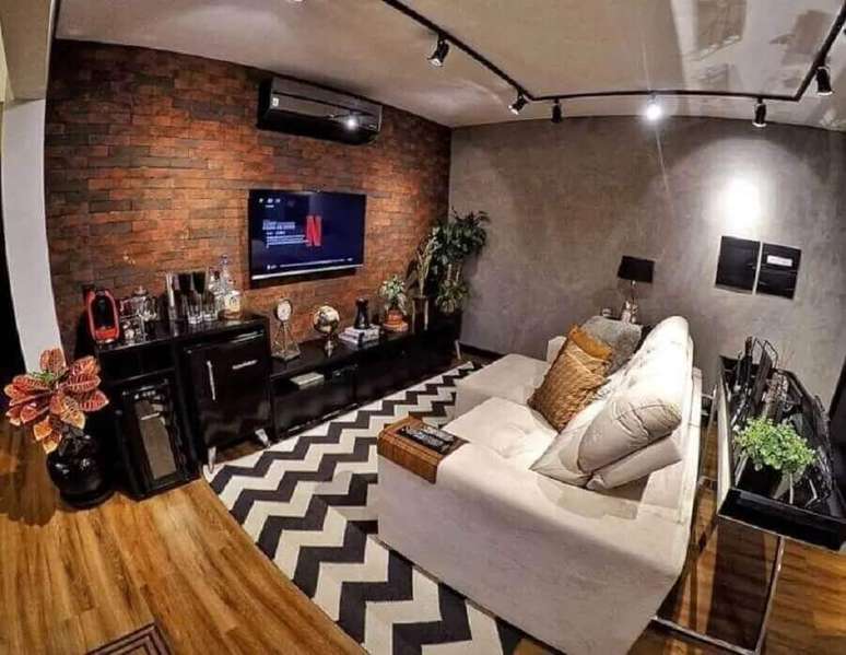 17. Ilumina&ccedil;&atilde;o de sala de estar industrial decorada com trilho de luz e parede de cimento queimado com tijolinho &ndash; Foto: Nosso Apartamento 63