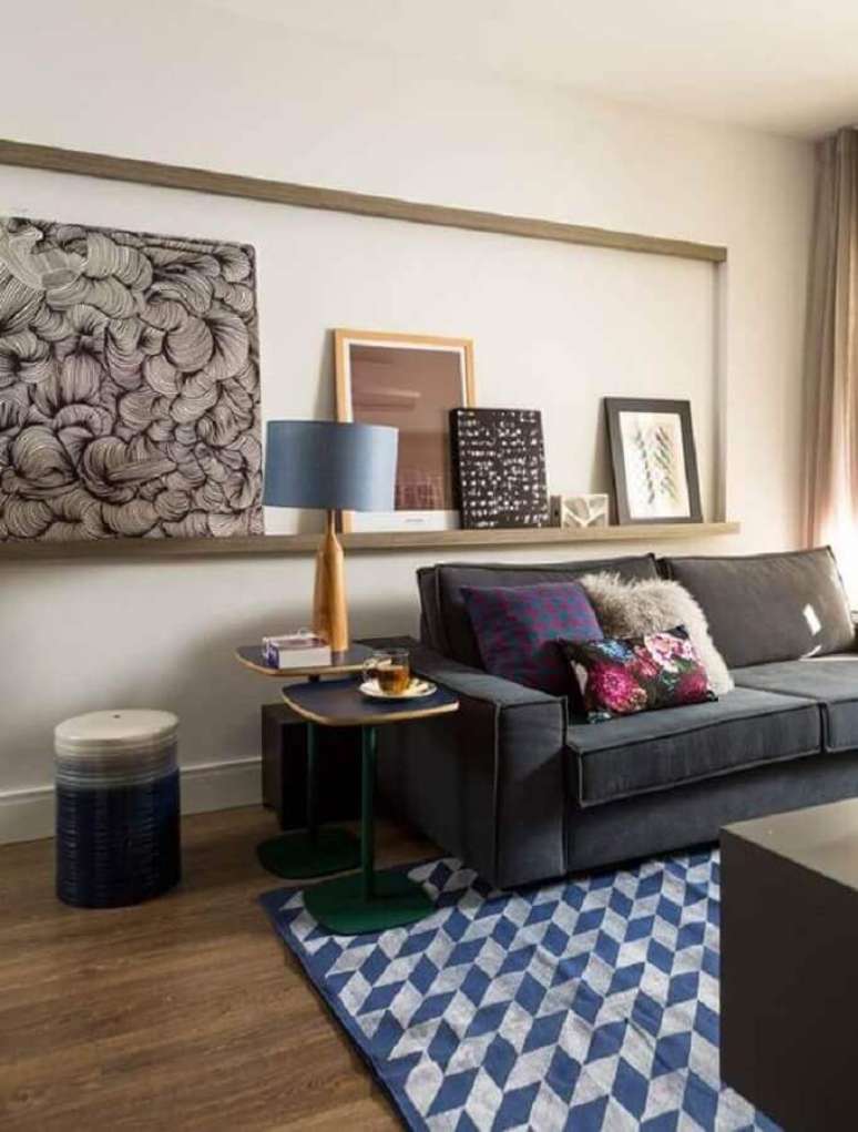 15. Iluminação de sala de estar decorada com prateleira para quadros e sofa cinza – Foto: Casa e Jardim
