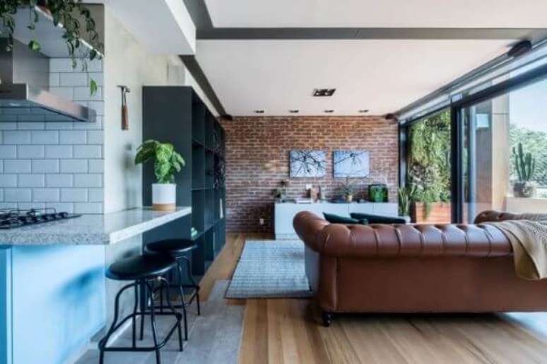 42. Sala com sofá marrom e papel de parede de tijolinho – Foto SP Estudio