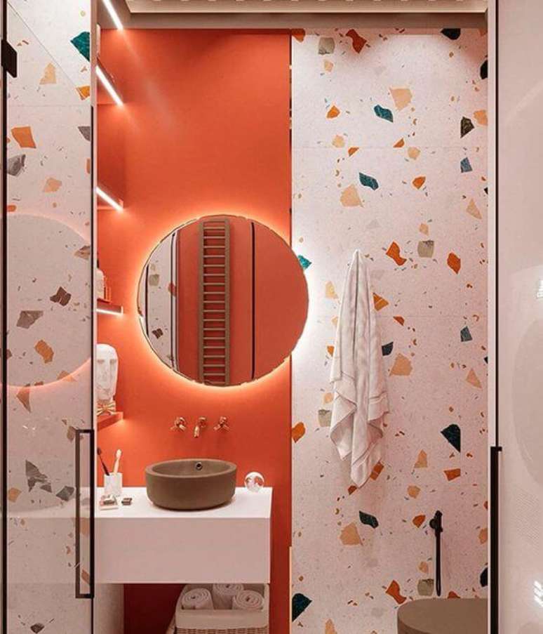 27. Banheiro retrô na cor coral com granilite de revestimento e espelho redondo com led – Foto Arkpad