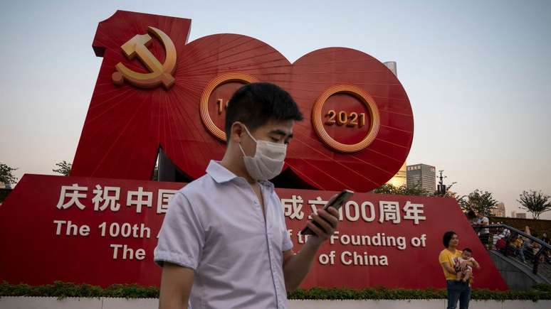 Pessoas tirando fotos em frente a uma placa que comemora o 100º aniversário da fundação do Partido Comunista da China em Xangai