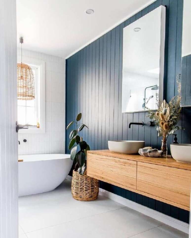 23. Gabinete suspenso para banheiro decorado com banheira de imersão e parede de lambri de madeira – Foto: Easycraft