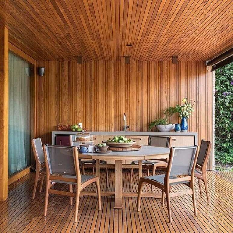 11. Casa com varanda decorada com mesa redonda e lambri de madeira – Foto: Três Arquitetura