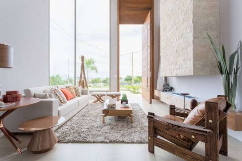 5. Sala sem tv decorada com lareira e poltronas criativas de madeira – Projeto Alex Bonilha