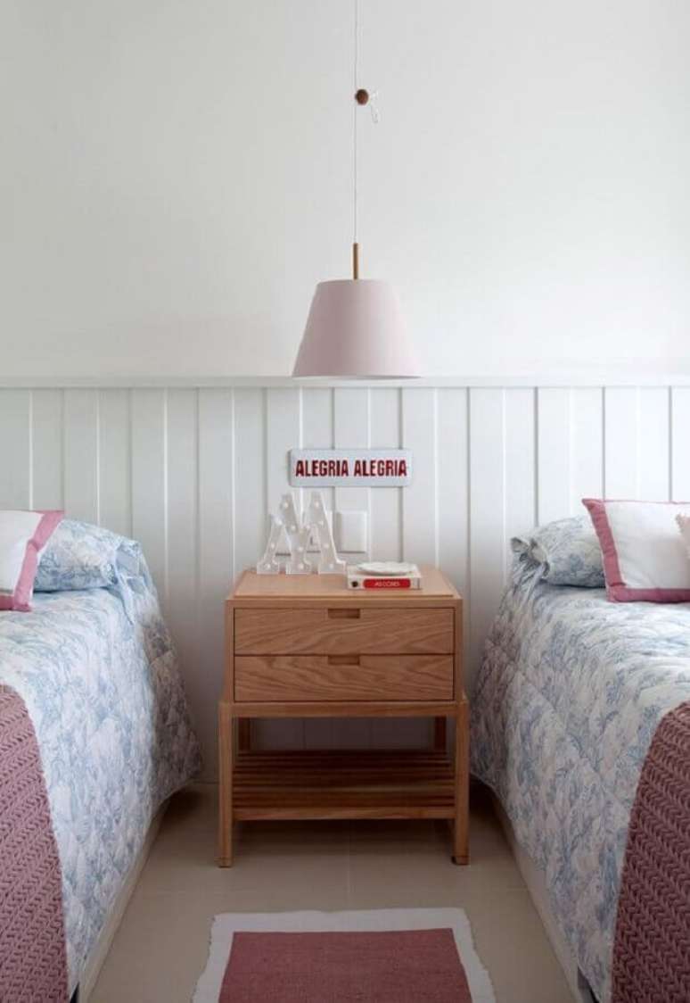 48. Quarto de solteiro compartilhado decorado com luminária rosa e lambri de madeira meia parede branco – Foto: Paula Magnani