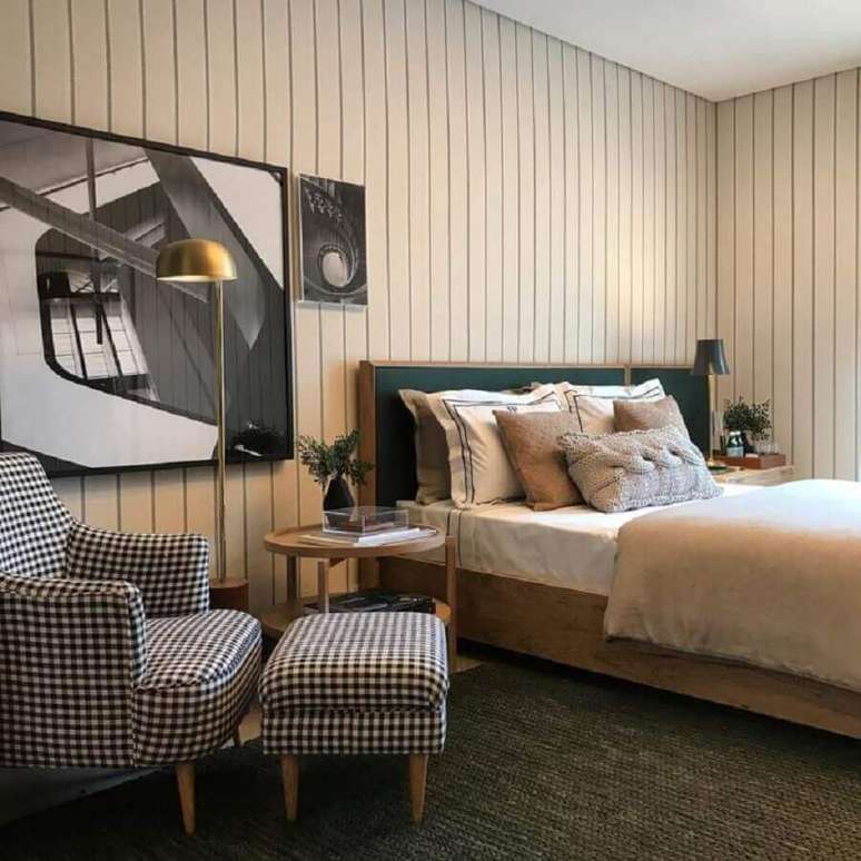 17. Decora&ccedil;&atilde;o de quarto de casal com lambri de madeira branco e poltrona xadrez com puff &ndash; Foto: Babi Teixeira