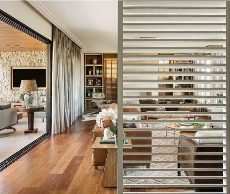 30. Divis&oacute;ria de madeira para sala com sof&aacute;s de couro e almofadas branca e bege &ndash; Foto AG Arquiteturas