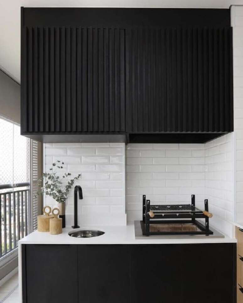 29. Azulejo tijolinho branco para área gourmet decorada com armários pretos planejados – Foto: Thais Helena Ribeiro