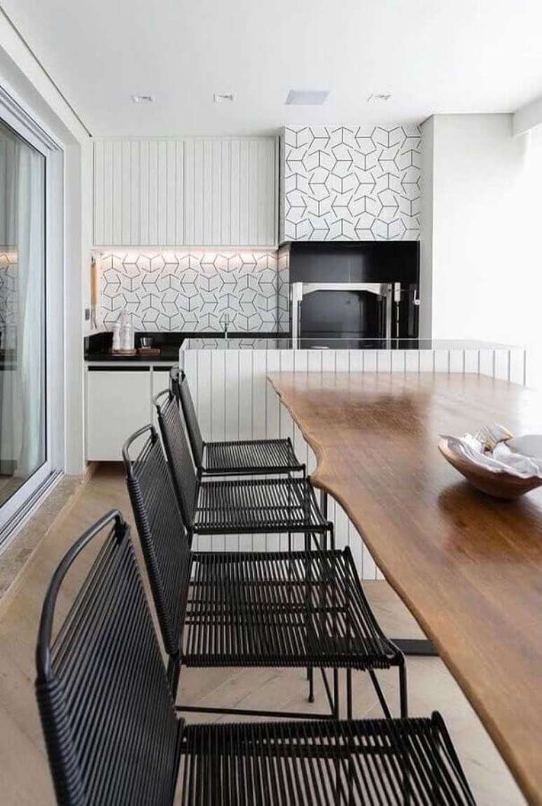 5. Azulejo branco para varanda gourmet decorada com mesa de madeira e cadeira preta moderna – Foto: Homedit