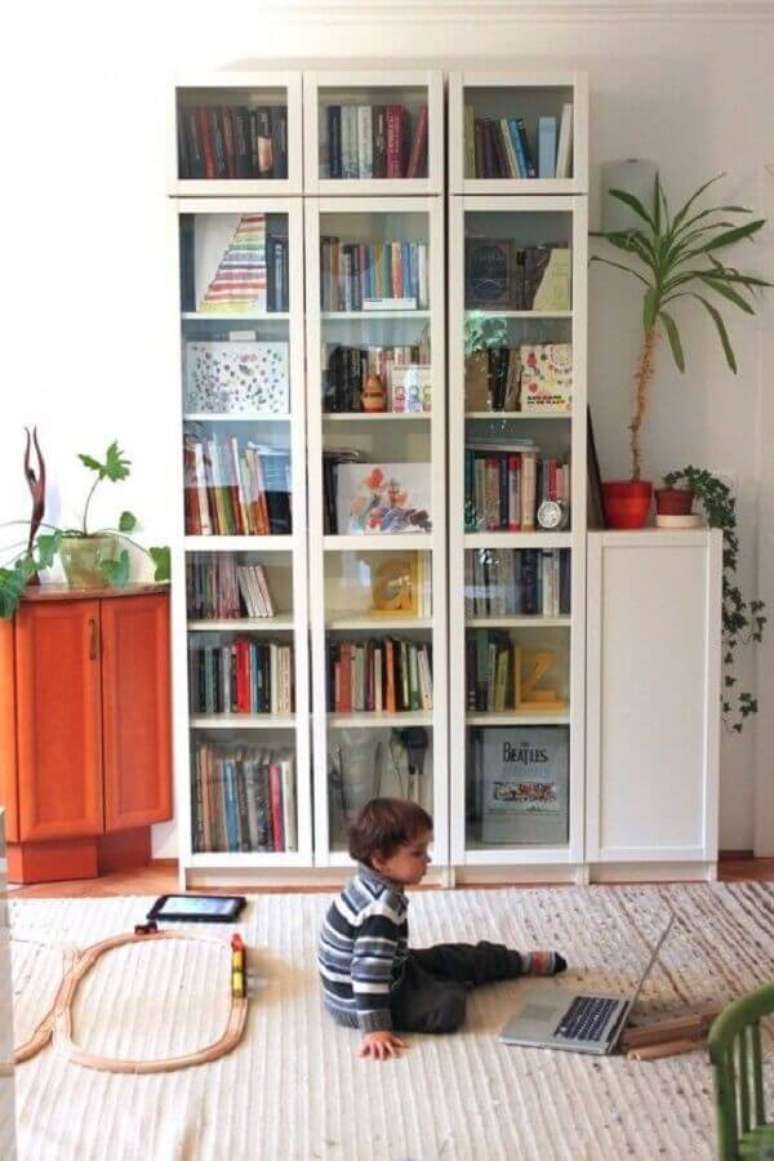 33. Decoração de sala branca com armário para livros fechado com porta de vidro – Foto: Apartment Therapy