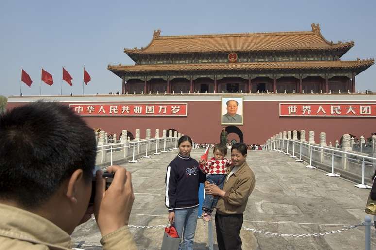 Turistas chineses posam para fotografias em frente ao retrato de Mao