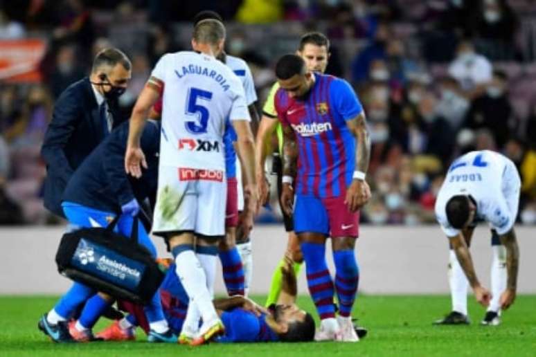 Agüero caído com a mão no peito após sentir dores torácicas (Foto: PAU BARRENA / AFP)