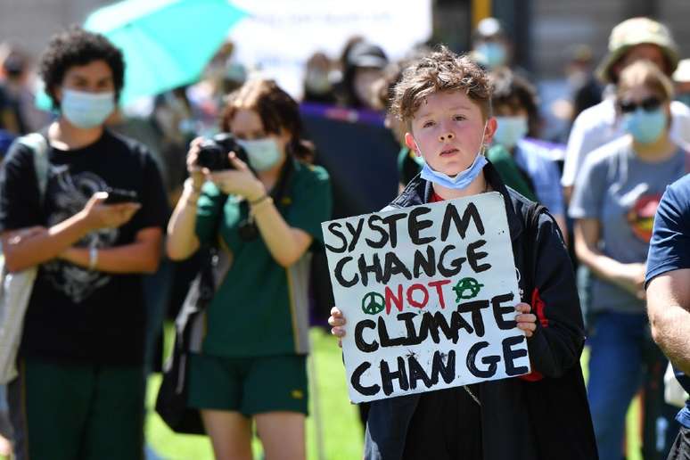 Menino com um cartaz que pede 'mudan&ccedil;a no sistema em vez de mudan&ccedil;a clim&aacute;tica'
