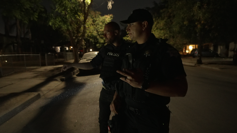 O oficial Nate Palomino procura cartuchos de armas em uma rua de Fresno