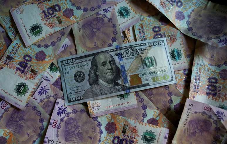 Nota de 100 dólares sobre notas de 100 pesos da Argentina
03/09/2019. 
REUTERS/Agustin Marcarian/Illustration/File Photo