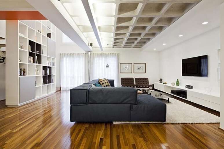 30. Sala de estar preta e branca com estante de nichos planejada atrás do sofá – Foto Stuchi e Leite