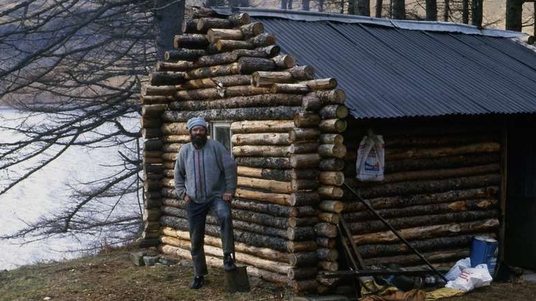 Ken em sua cabana de troncos, pouco depois de terminar a constru&ccedil;&atilde;o dela em meados da d&eacute;cada de 1980
