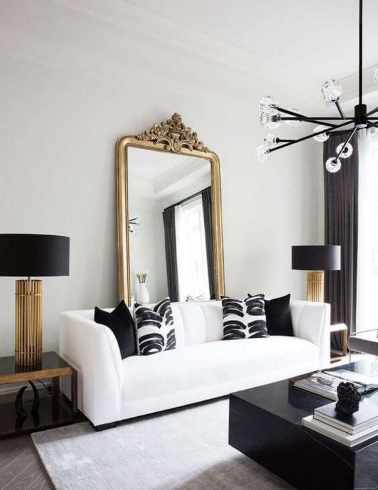 5. Sala com espelho dourado de chão atrás do sofá branco e enfeites pretos – Foto My Domaine