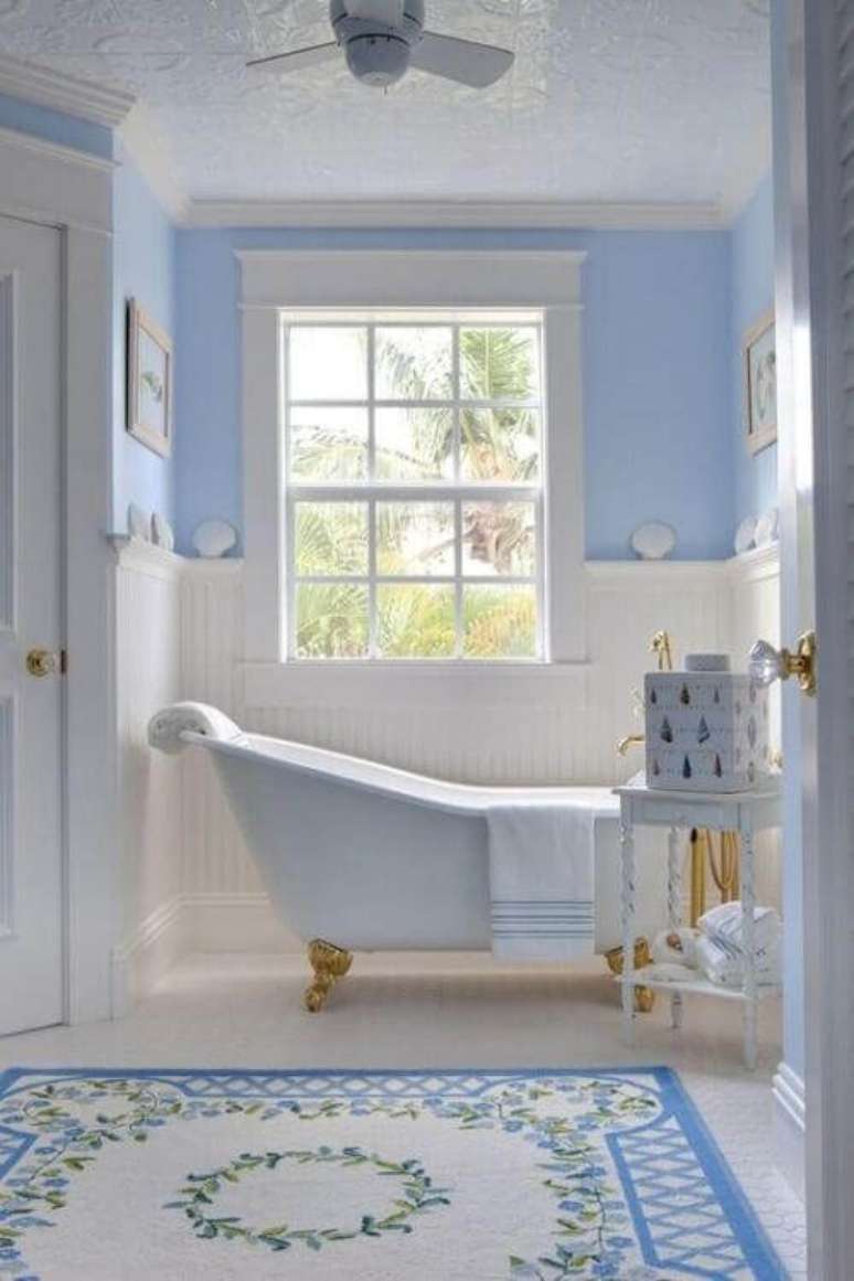 35. Banheira vitoriana branca com dourado no banheiro azul delicado e pequeno – Foto Bornin May