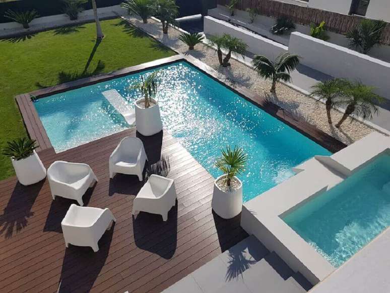 5. Poltronas brancas para &aacute;rea externa com piscina grande e deck de madeira &ndash; Foto: habitissimo