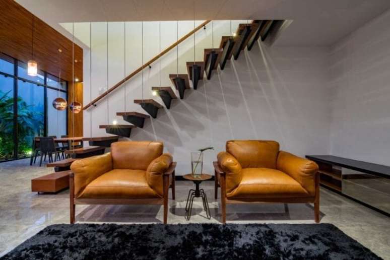31. Sala com poltronas de couro e escadas modernas – Foto Estudio Haa