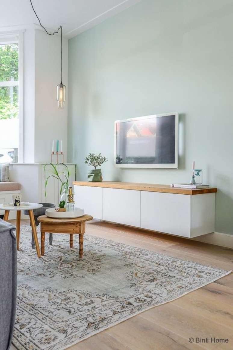 33. Sala com parede verde pastel e móveis brancos – Foto Binti Home Blog