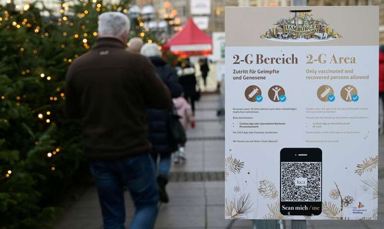 Pessoas aguardam em frente a placa que sinaliza permissão para entrada somente de vacinados ou recuperados da Covid-19 em mercado de Natal em Hamburgo
22/11/2021 REUTERS/Fabian Bimmer