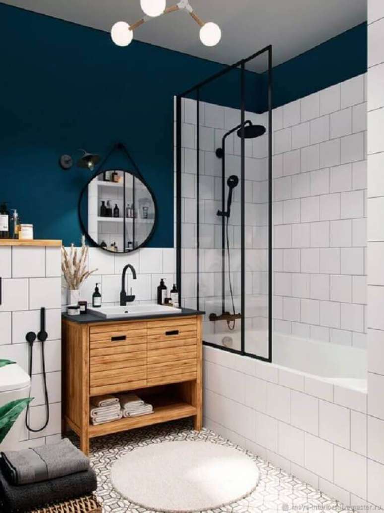 13. Banheiro industrial azul e branco decorado com gabinete de madeira e espelho redondo – Foto: Home Fashion Trend