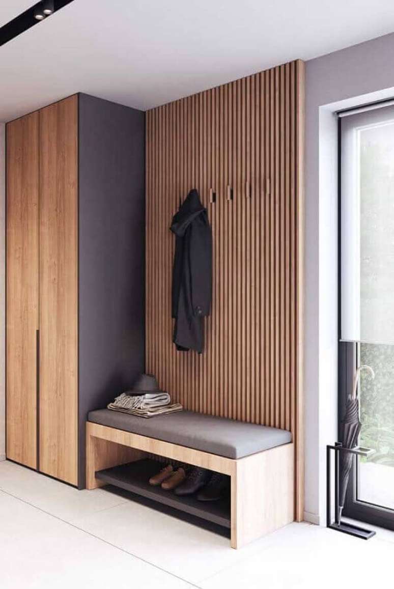 14. Decora&ccedil;&atilde;o de hall de entrada com banco estofado e parede de ripas de madeira &ndash; Foto: Decor F&aacute;cil