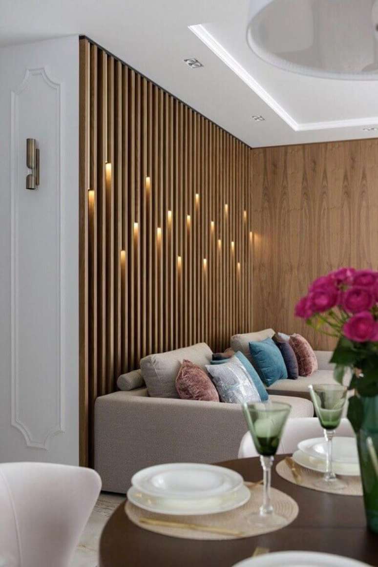 36. Parede de madeira ripada com iluminação para decoração de sala de estar – Foto: Decor Fácil