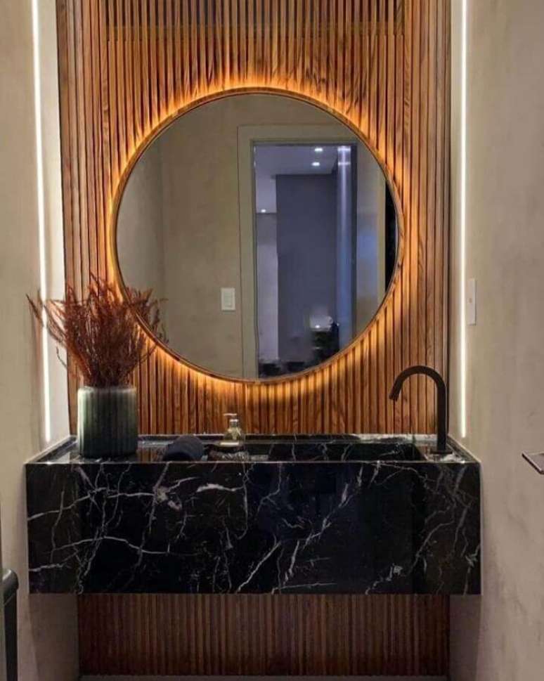 43. Parede ripada para banheiro pequeno decorado com espelho redondo e bancada de mármore preto – Foto: Romero Arquitetura