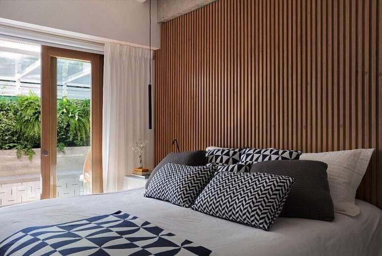 20. Decoração de quarto de casal com almofadas para cama e parede ripada – Foto: PKB Arquitetura