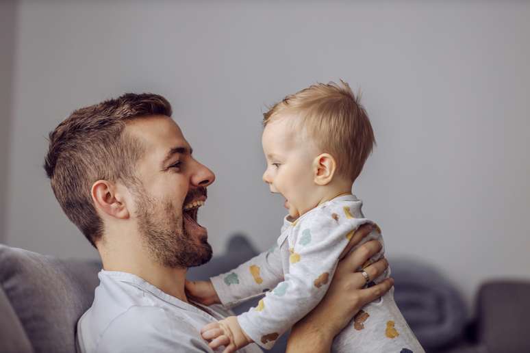 Bebê e homem sorrindo cara a cara
